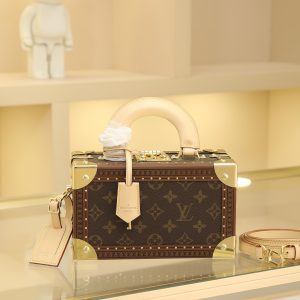 Box Bag Valisette Trésor Handbag Case For the Spring/Summer 2021 collection, Women's Artistic Director Nicolas Ghesquière collaborated with Women's Leather Goods Design Director Johnny Coca to introduce the new wearable Valisette Trésor handbag case. Its form and dimensions draw inspiration from the brand's iconic Coffret Trésor 20 case.Originally a compact storage case for jewelry or other precious treasures, it has been reimagined as a soft, wearable handbag. Fully functional, it combines traditional leather craftsmanship with authentic trunk-inspired details—including Lozines vulcanized fiber trim with studs and an S-shaped padlock with key.Estimated delivery time for this item exceeds nine months. Dimensions: 22.5 x 14.5 x 11.5 cm.